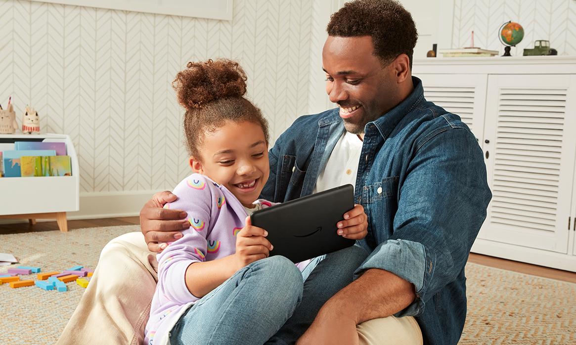 Young girl with her father playing with her kindle and smiling