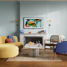 A wide shot Amazon Ember Artline TV in a bright-themed living room setting displaying colorful art while in idle mode.