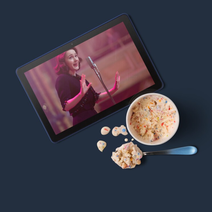 Sobre un fondo azul una tablet con una imagen de una serie de Prime Video. Al lado, un cuenco de helado con una cuchara llena. 