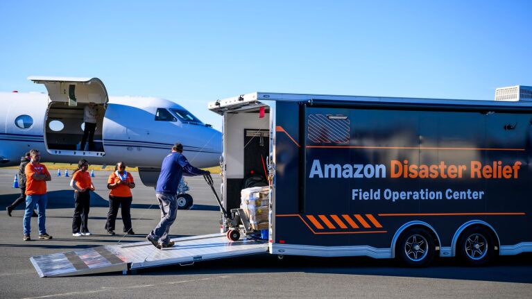 Amazon Disaster Relief trailer on tarmac with workers loading supplies from cargo plane