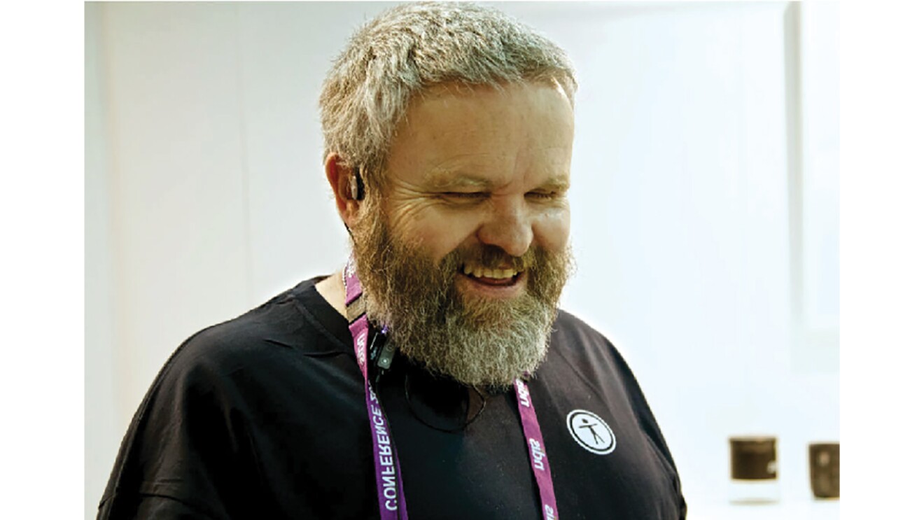 David, smiling and holding a smartphone.