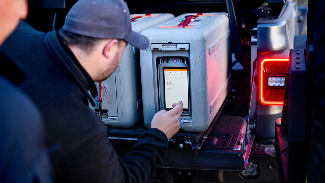 An image of a man using a touch screen on a large metal suitcase.