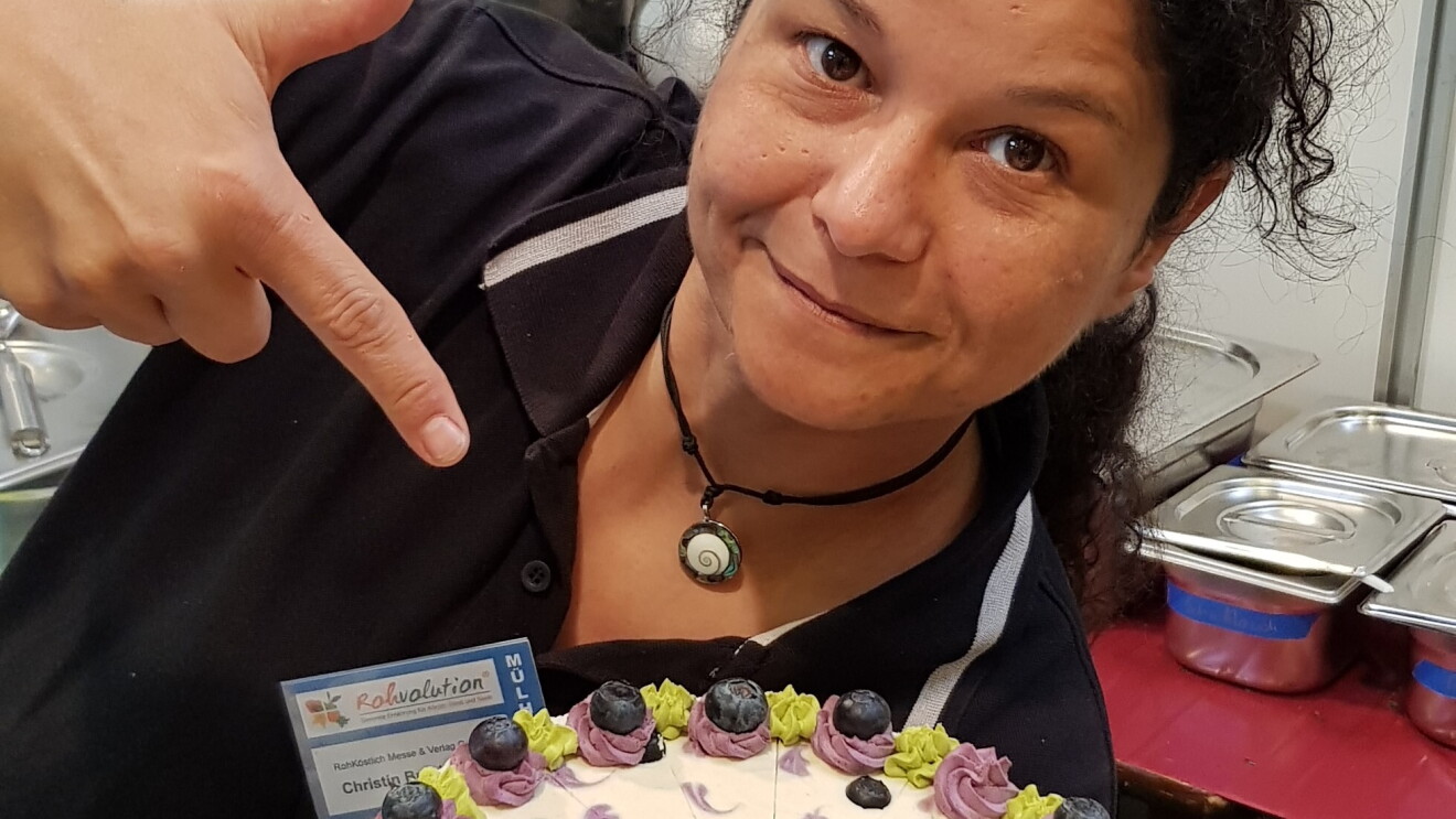Eine Frau zeigt auf eine Torte, die sie in der Hand hält