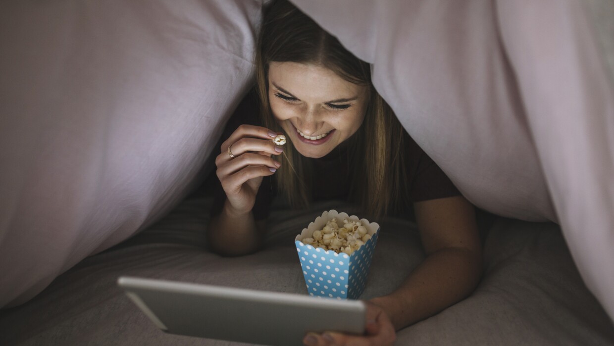 cheerful-woman-watching-film-blanket-tent