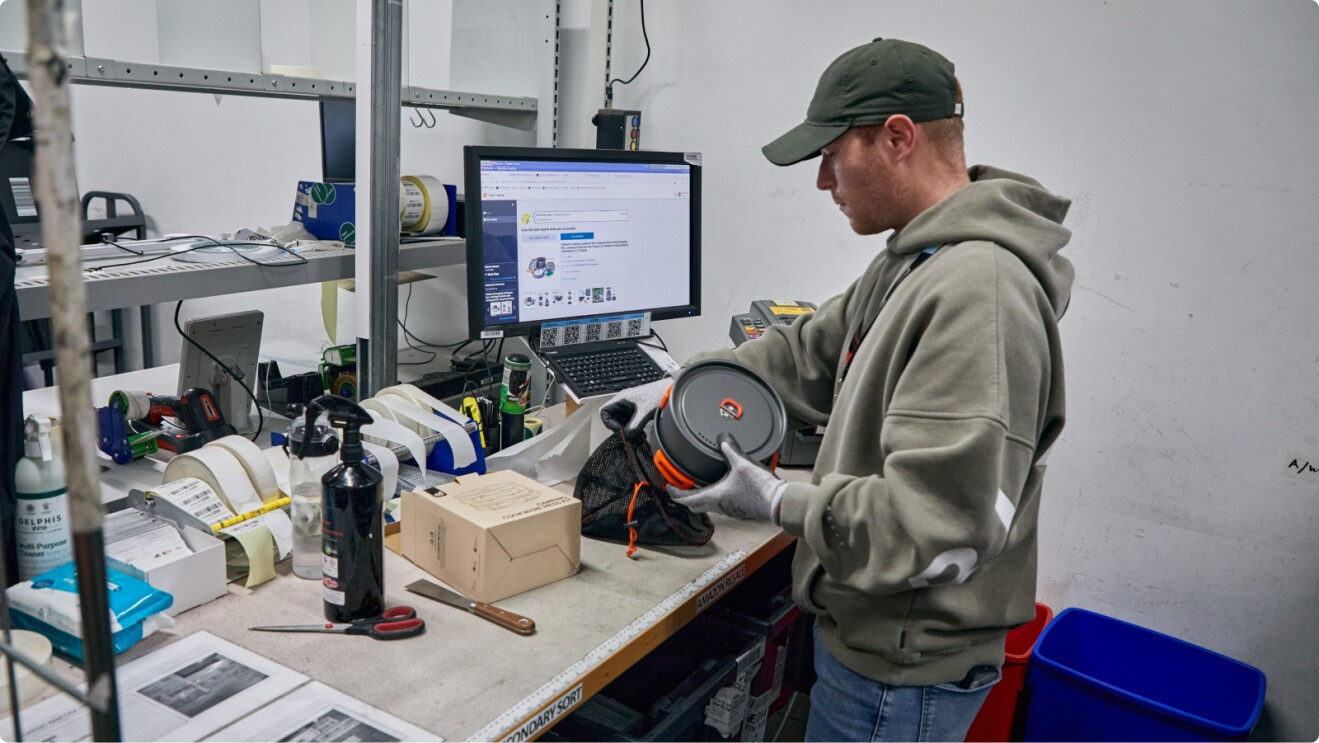 Worker inspecting product in Amazon fulfilment centre workspace