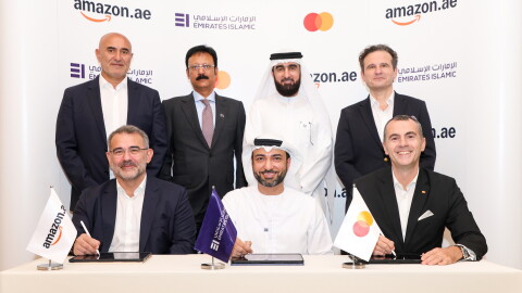 Amazon, Mastercard, EIB employees proudly sign a partnership in front of a cobranded rollup