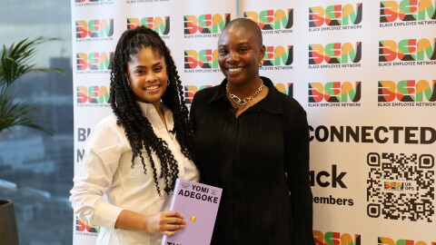 Two young women standing in front of a Black History Month banner 
