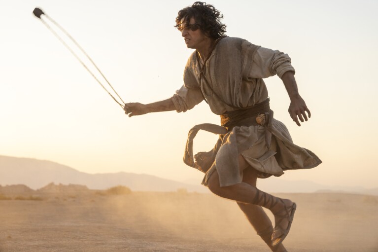 A still from the series House of David showing a young man in the desert holding a sling