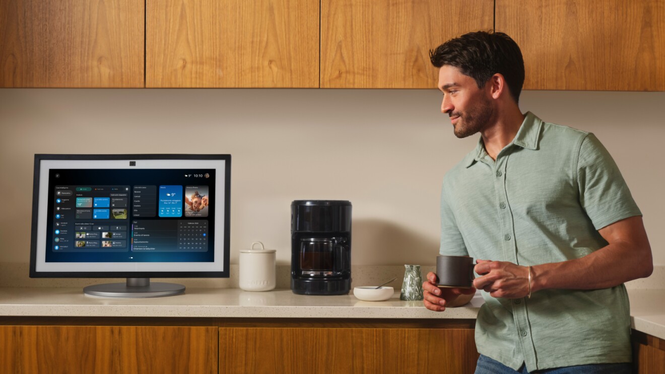 man in green shirt drinking a coffee in the kitchen next to his Alexa+ device