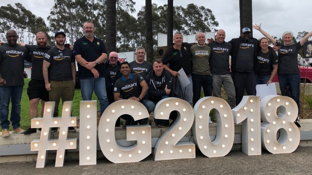 An image of a group of people standing in front of a light-up sign that says "#IG2018"