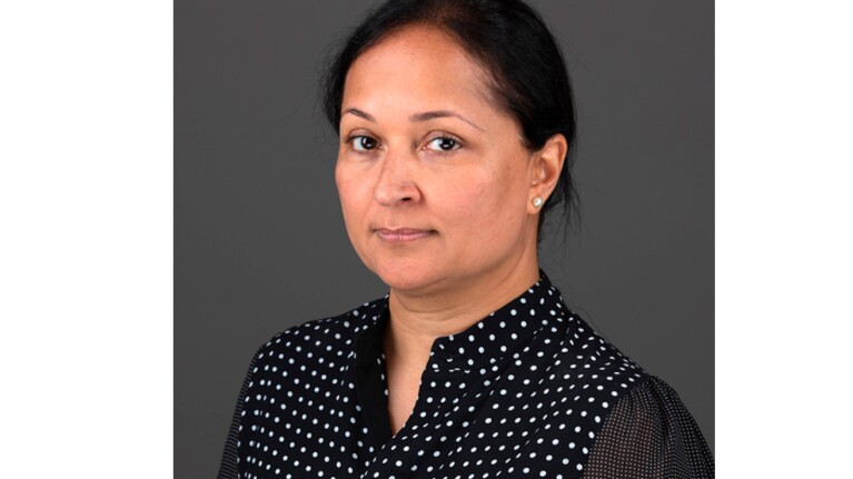 A headshot image of a woman with a dark gray background behind her.