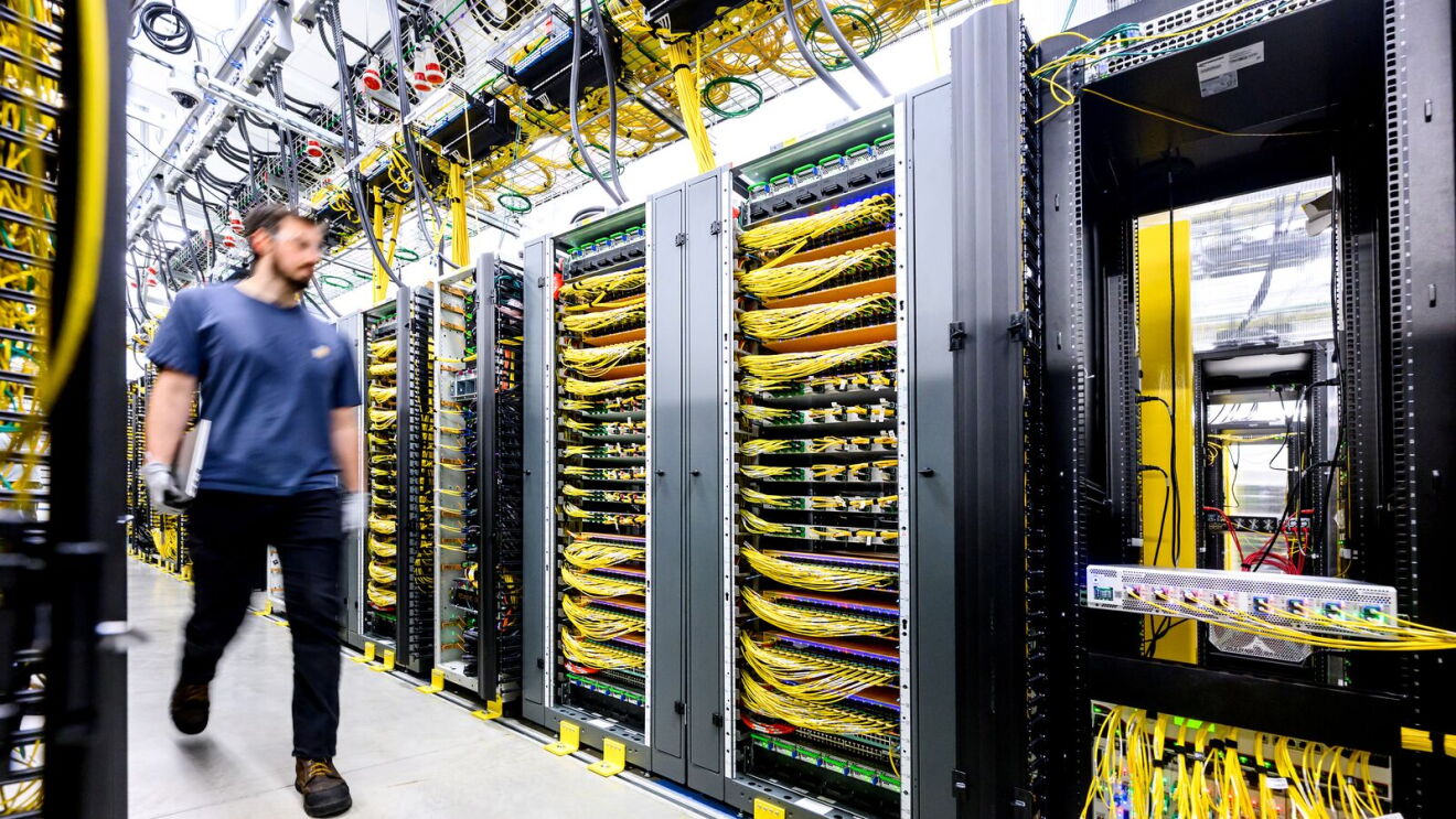 A data center technician walking between server racks within a data center