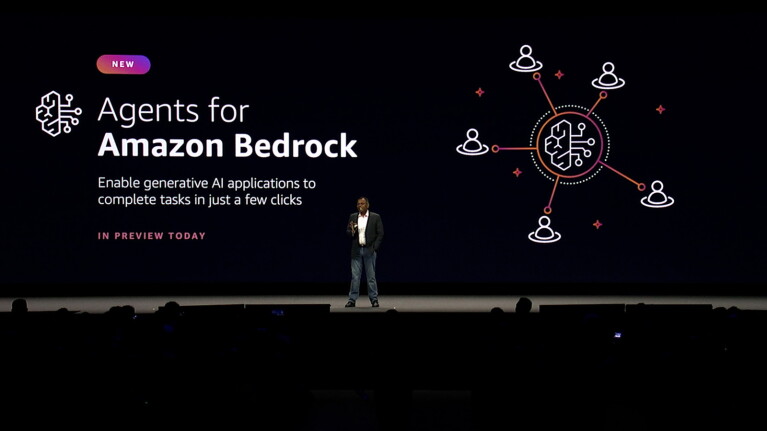 A photo of VP Swami Sivasubramanian speaking on stage at AWS Summit New York. Behind him is a screen that states, "Agents for Amazon Bedrock".