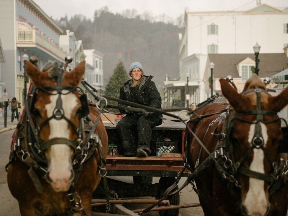 A woman rides a horse and dray carriage to deliver Amazon packages to the people that live on Mackinac Island.