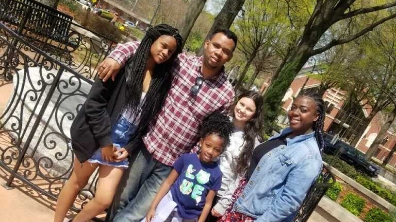 A man and his family stand in a park together