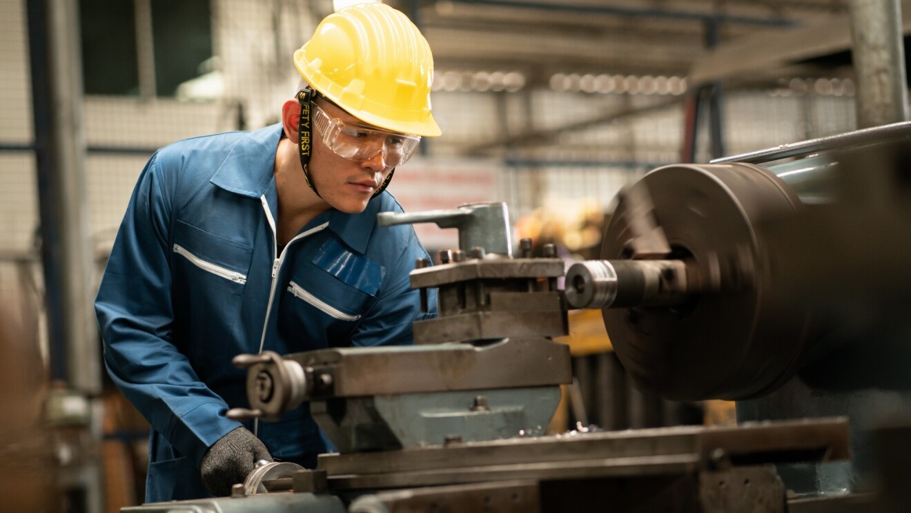 一个男人穿着安全装置与机械工作。