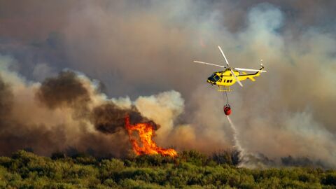 Image of a helicopter dropping water over a forest fire