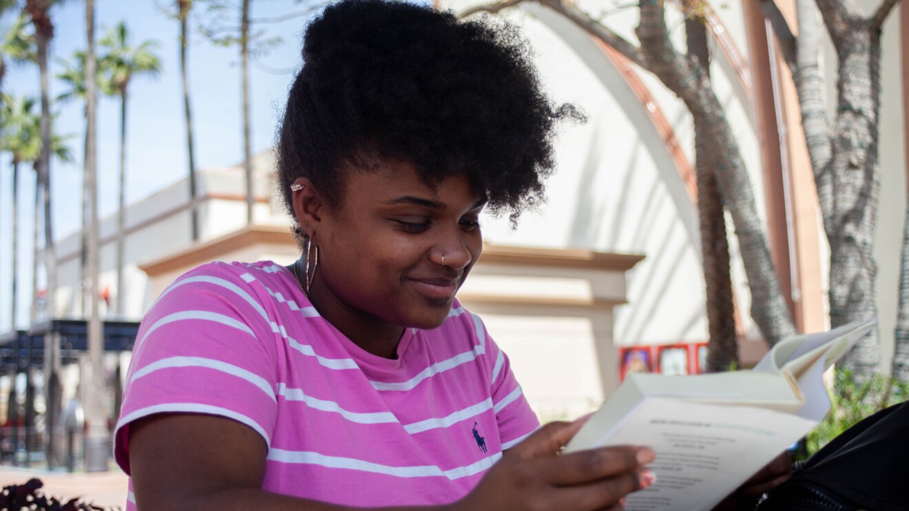 外一个女人坐在桌子的形象微笑而读一本书。