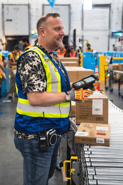 Un employé d'Amazon souriant tout en scannant une boîte dans un entrepôt