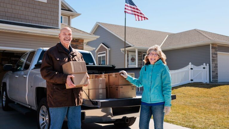 A photo of the owners of Spice Isle Sauces loading boxes for shipping in the back of a pick up truck.