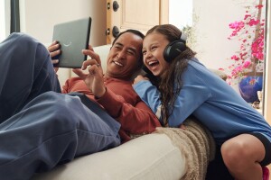 A father and daughter share a laugh while streaming on their Fire tablet. 