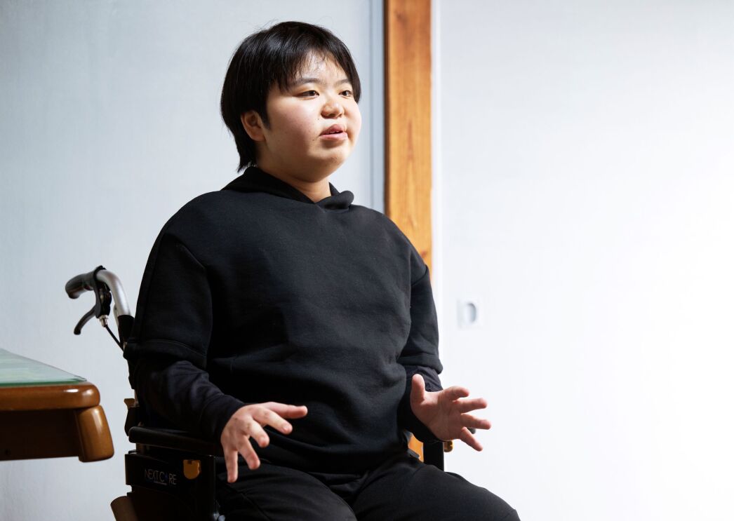 車椅子に座っている男性が手のジェスチャーで説明しているようだ。