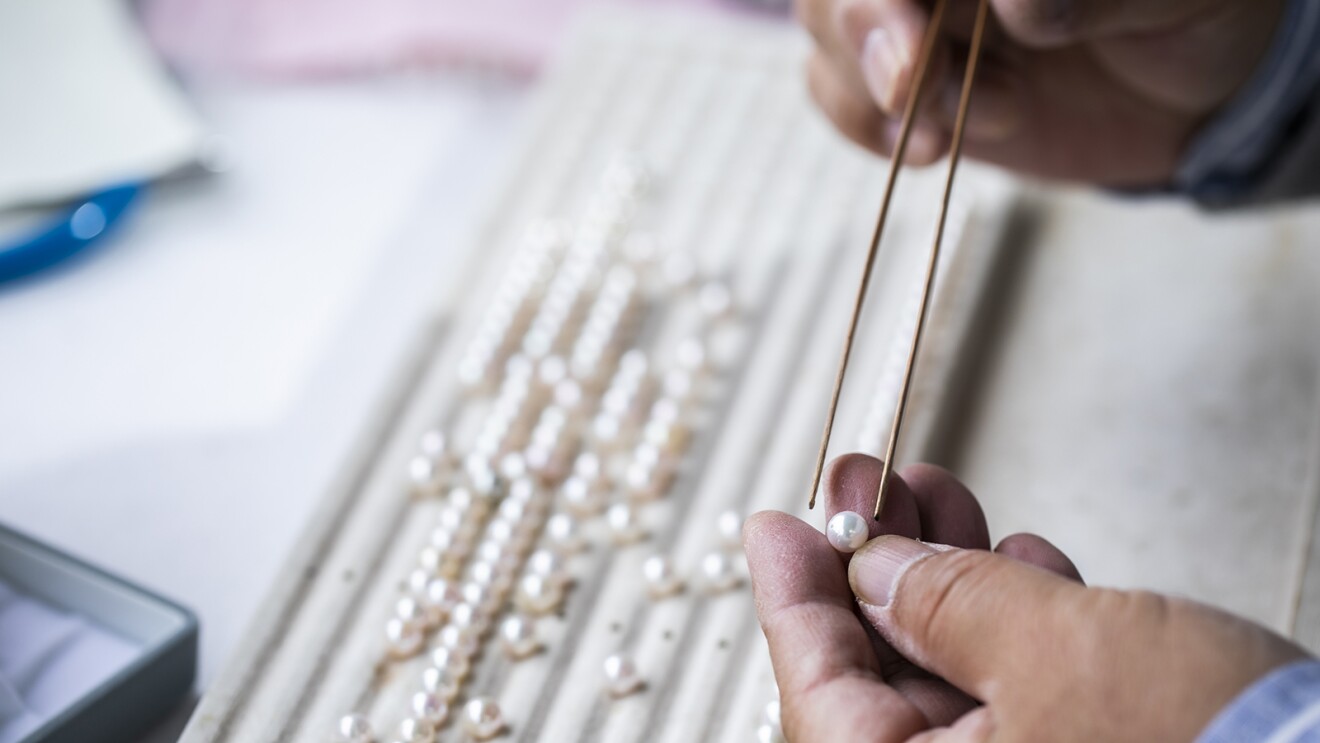 ピンセットで真珠をつまみ、確認している手元