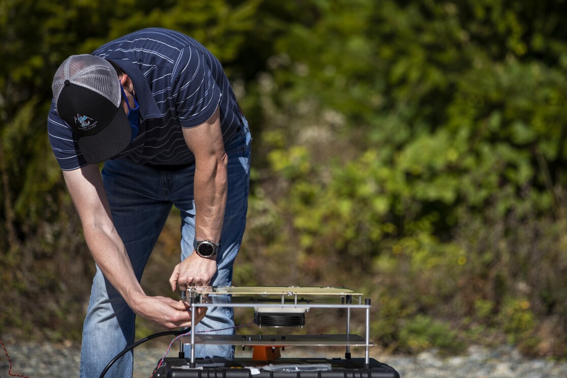 An image of a man testing the antenna on Project Kuiper in a field.