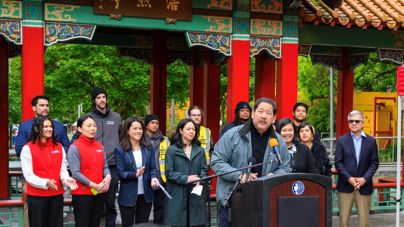 Mayor speaking at outdoor event in Chinatown setting