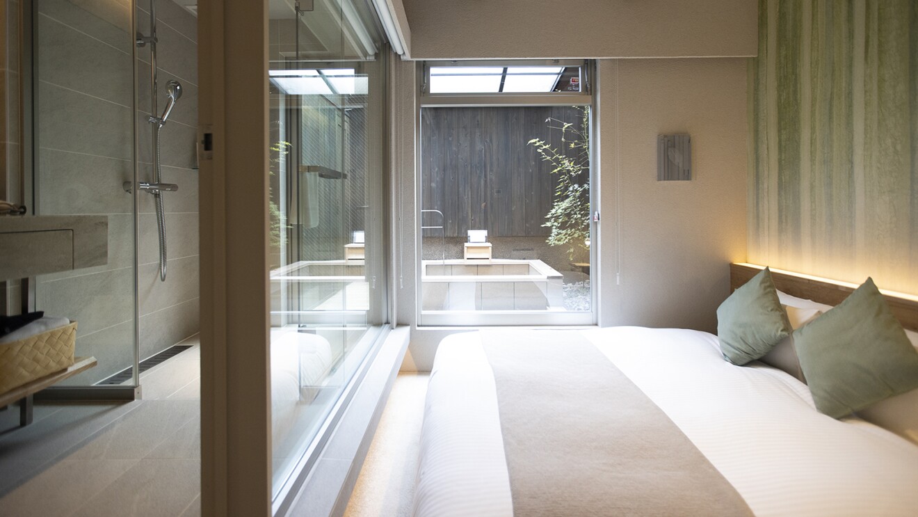 ベッドの向こうの窓の先に露天風呂が見える