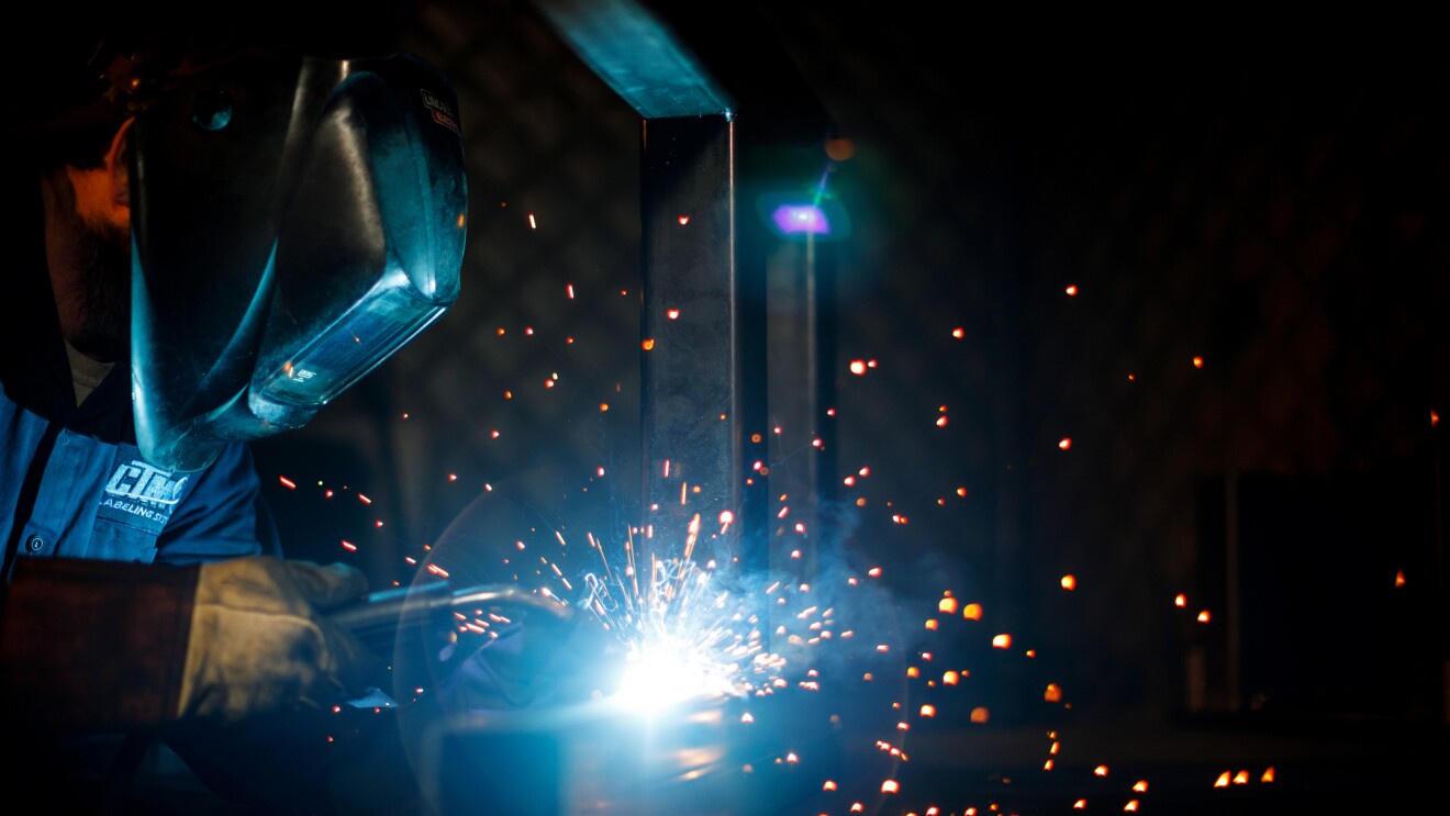 Sparks fly as a a welder works on a metal structure.