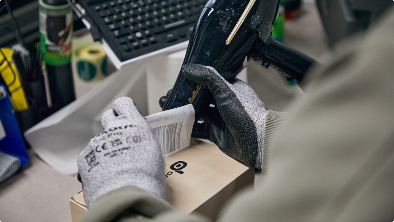Gloved hand removing barcode label from box using hairdryer heat
