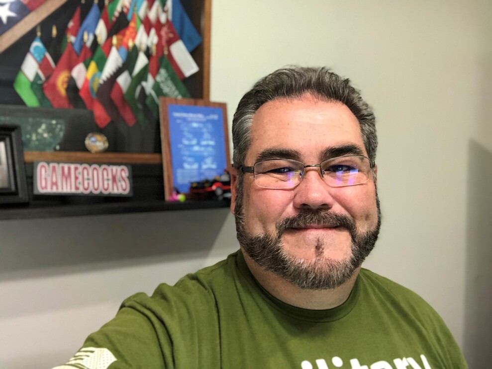 An image of a man smiling for a selfie photo in his home.