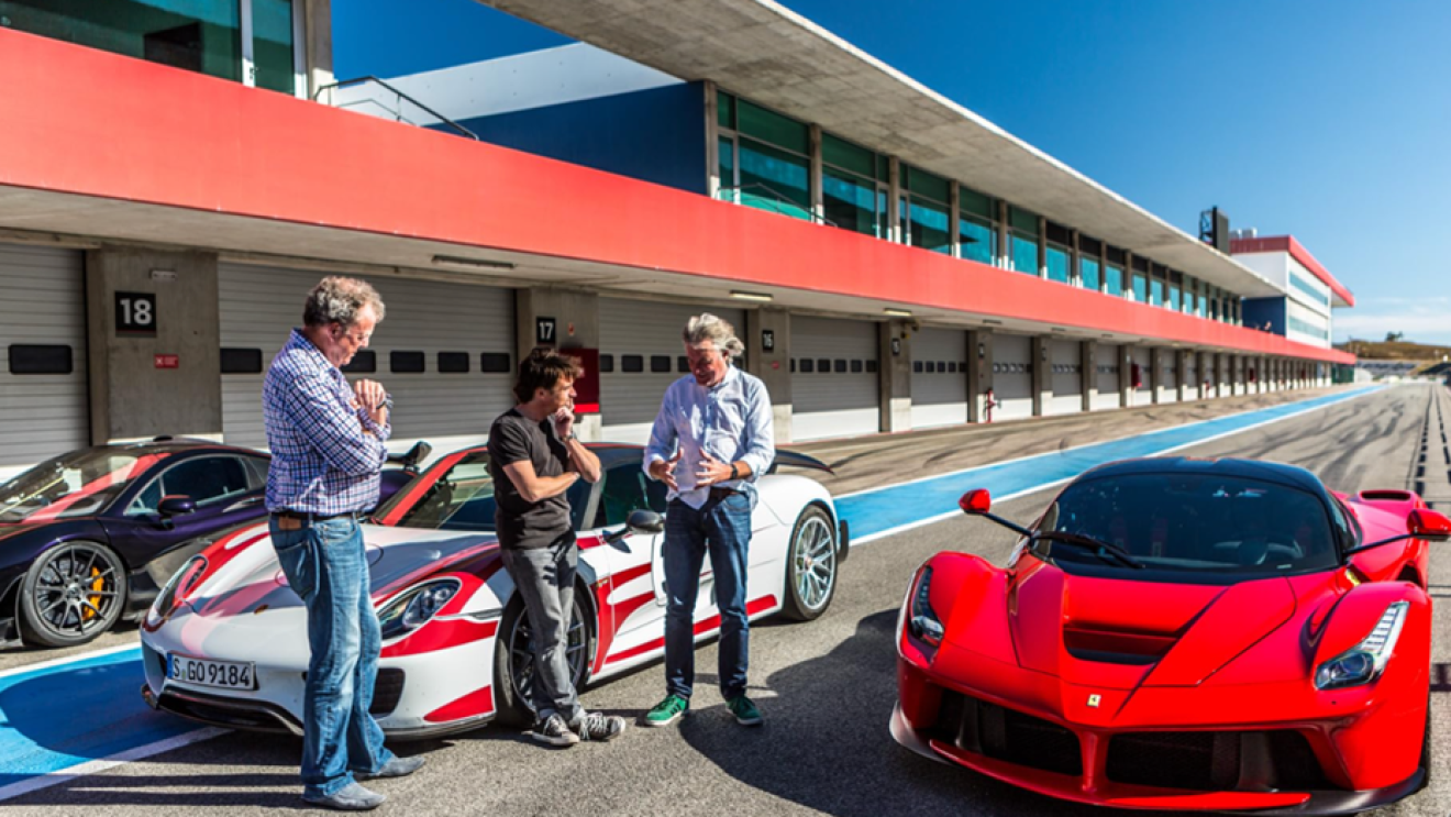 Jeremy Clarkson, Richard Hammond and James May stand next to three sports cars on a race track