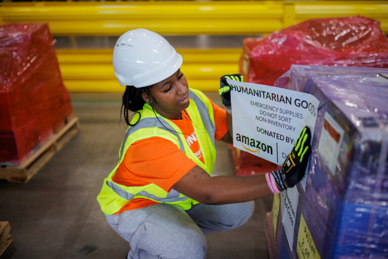 Warehouse worker labeling a pallet of humanitarian supplies donated by Amazon