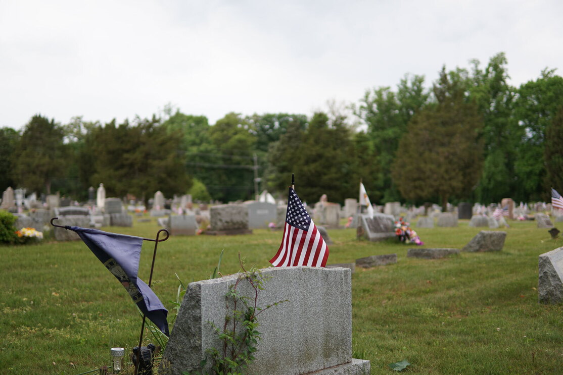 An image of Warriors@ members placing wreathes and flags on veterans' graves.