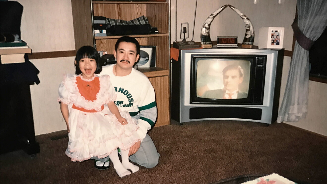 Janet T. Phan and her dad smiling at the camera in a living room.