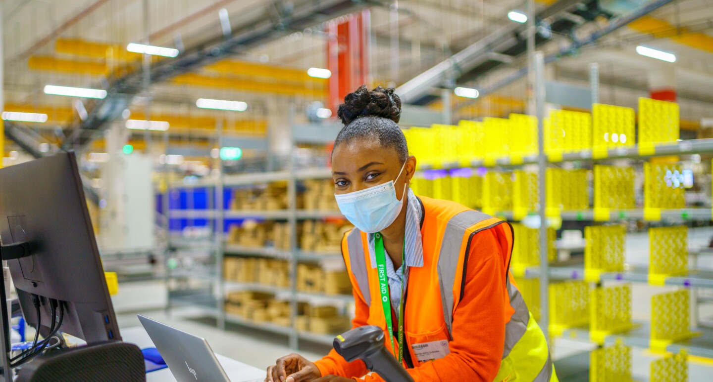 Junge Amazon Mitarbeiterin im Logistikzentrum am Rechner