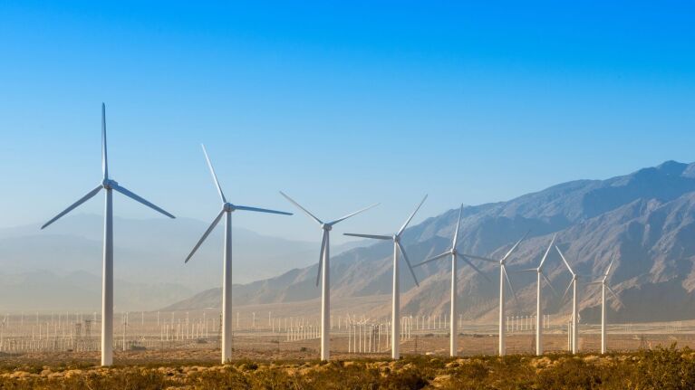 Wind turbines in a desert valley with mountains in the background