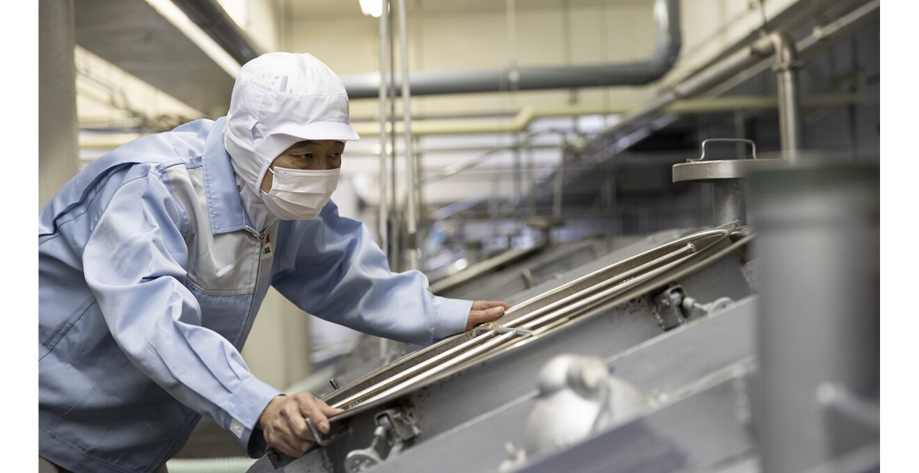 マスクと帽子ですっぽり頭を覆い、並べられたタンクをチェックしている写真