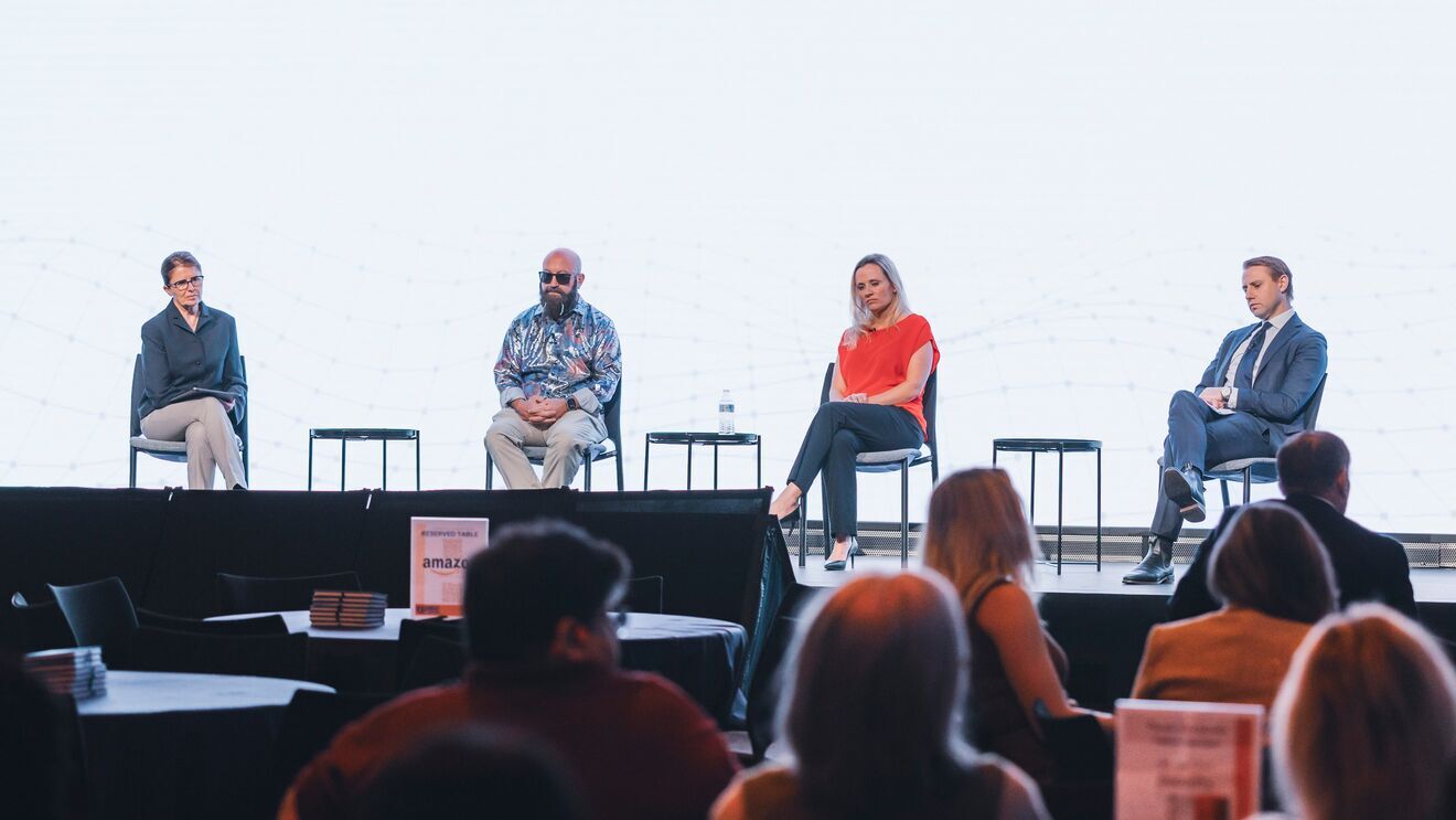Panel discussion with four speakers on stage addressing audience