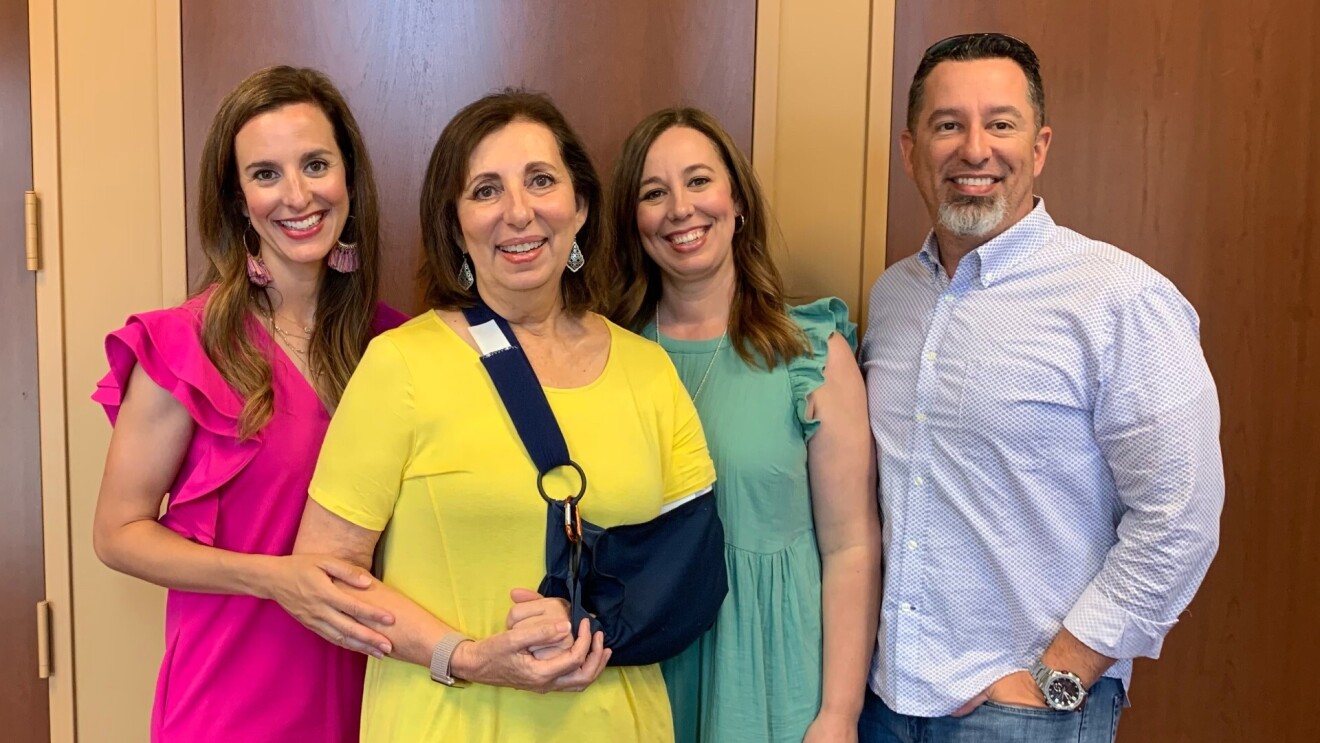 Rebecca wears a sling supporting her left arm while her, her two daughter, and son smile for the camera.