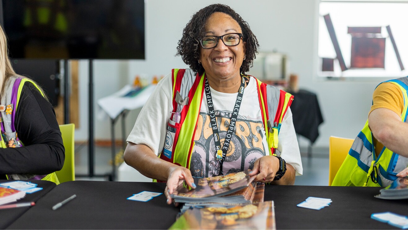 An image of an Amazon employee volunteer holding a stack of books to give away. 