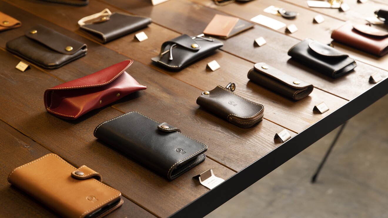 店内のディスプレイ用テーブルに並べられた革の小物類。メガネケース、スマホケース、キーケースなど