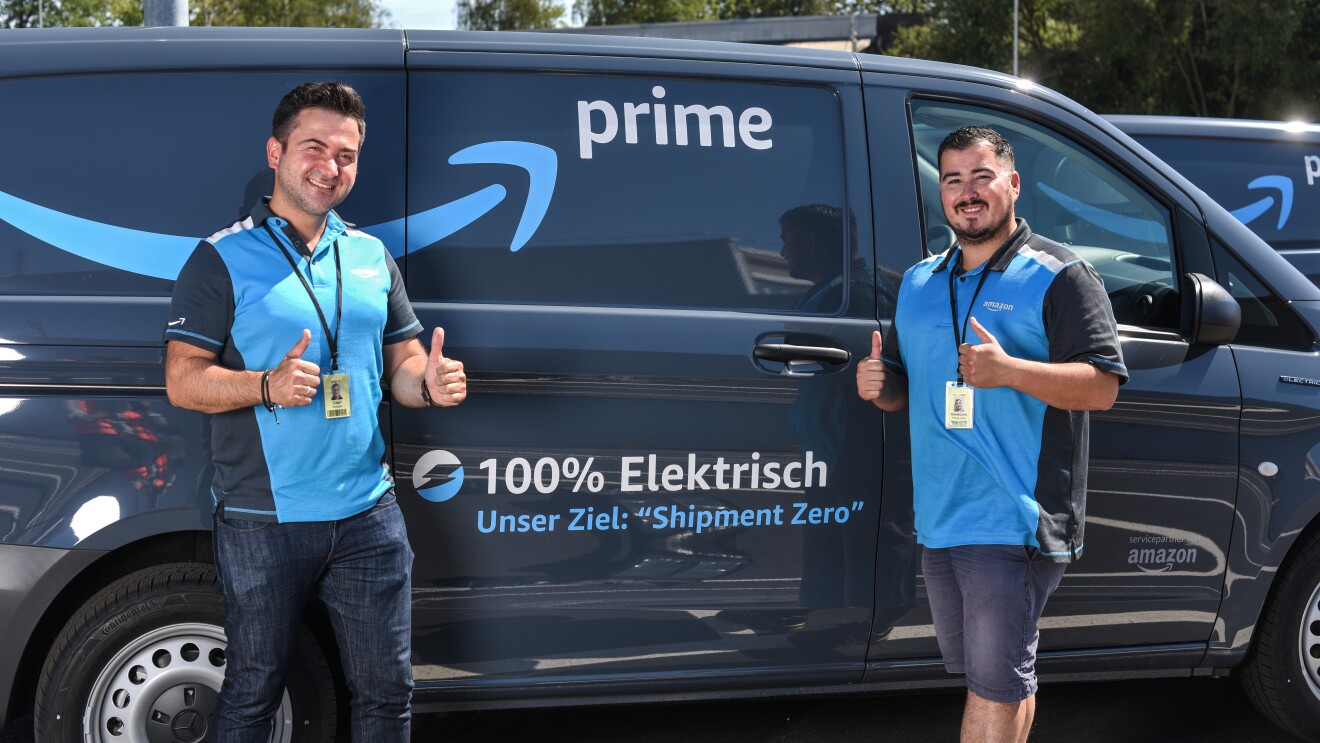 2 junge Männer in blauen Amazon Shirts vor einem Prime Lieferfahrzeug.