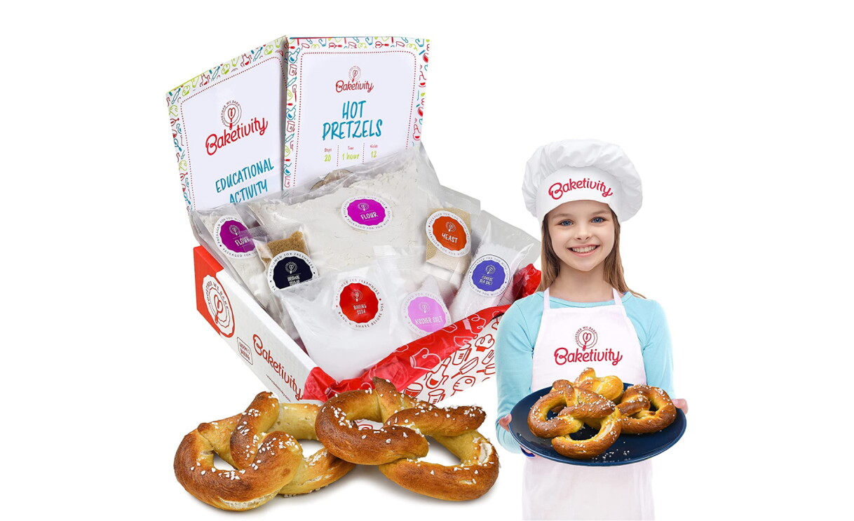A photo of a pretzel making kit, made by Bakeivity. The photo also includes a child dressed as a chef holding a plate of pretzels. 