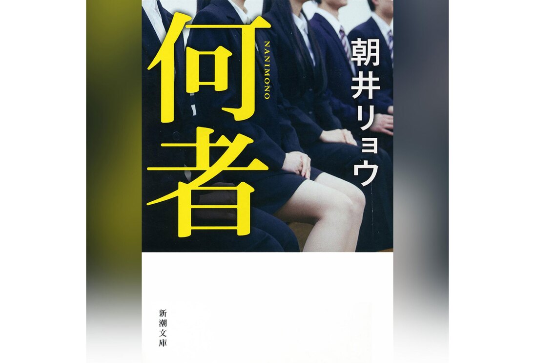 グラデーション背景に、縦長の書籍表紙。上側に顔から下だけ見えるリクルートスーツの人々が並んで座る様子、左側に大きく黄色で「何者」の字。下側は白背景、左隅に小さく「新潮文庫」の字。