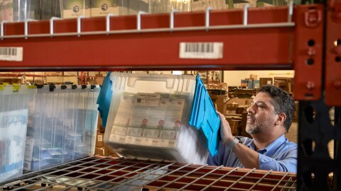 一个男人堆垃圾箱装满产品在架子上。