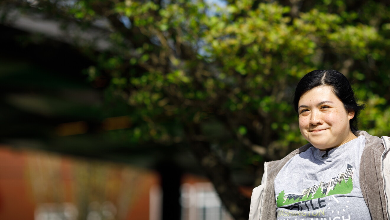 Prime Now associate Erika Lopez is smiling as she stands outside. There is a tree in the background.