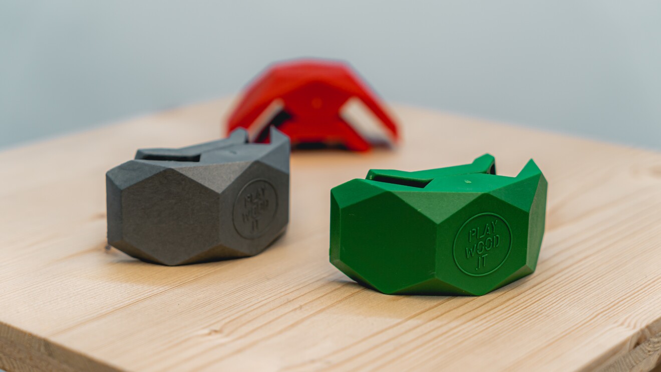 Tre morsetti Playwood in verde, grigio e rosso su una superficie di legno